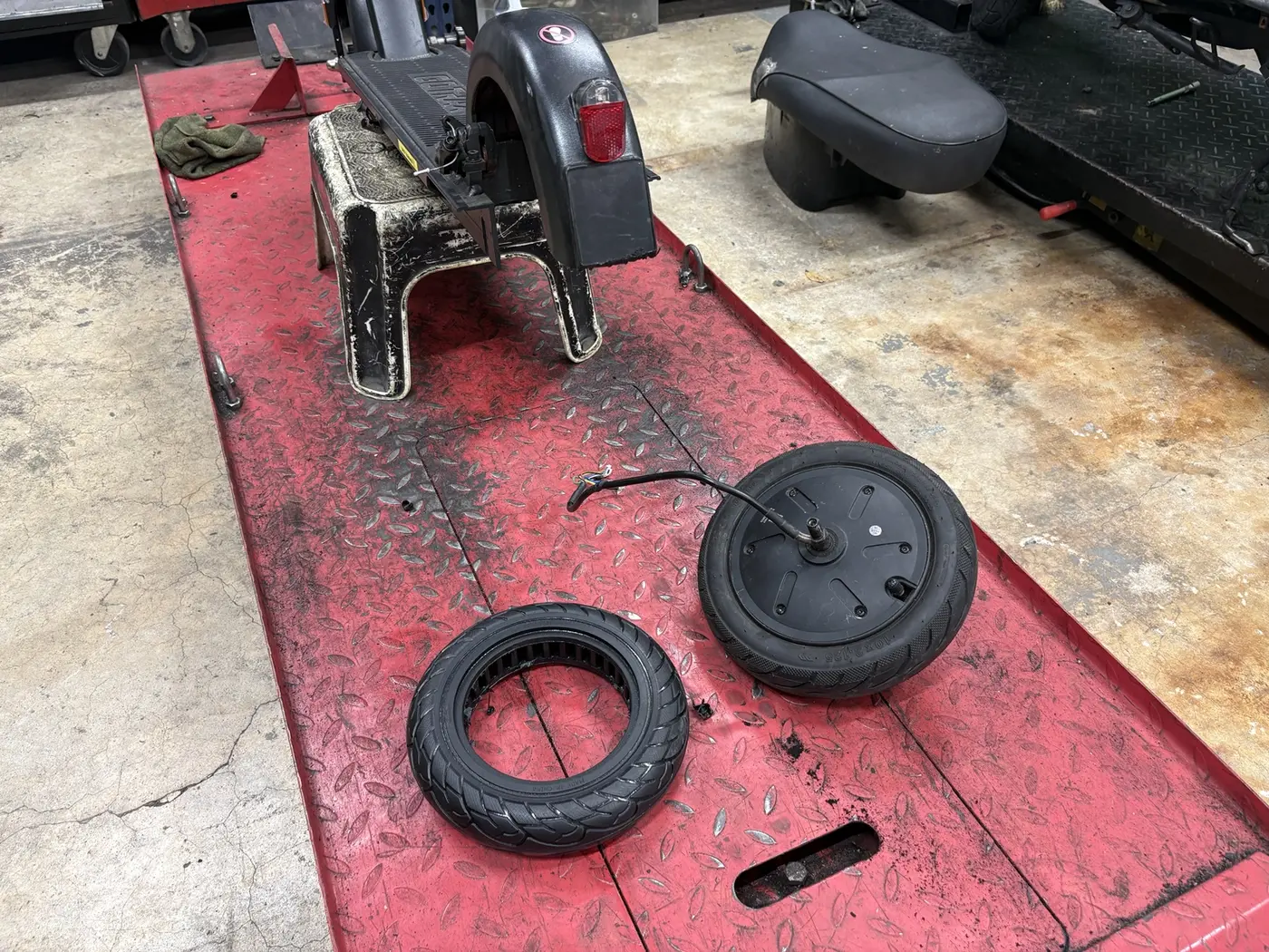 Electric scooter tire repair in progress with the rear motor wheel removed
